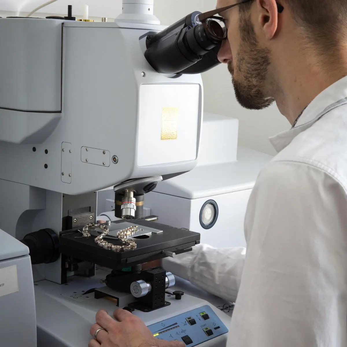 Tyler & Co-expert die een juweel onder de microscoop onderzoekt